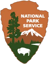 The National Park Service Arrowhead logo. An arrowhead with a brown background containing the words National Park Service and silhouettes of a mountain, a sequoia tree, a lake, and a bison.�